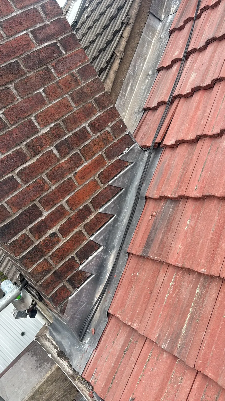 Red tiles finished against a brick wall with lead, Dawn Roofs Ltd